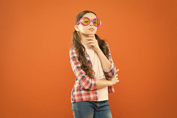 Smart and confident. Adorable child with smart look through fancy glasses. Fashionable small kid wearing smart glasses. Little smart girl on orange background - Fotoğraf, Görsel