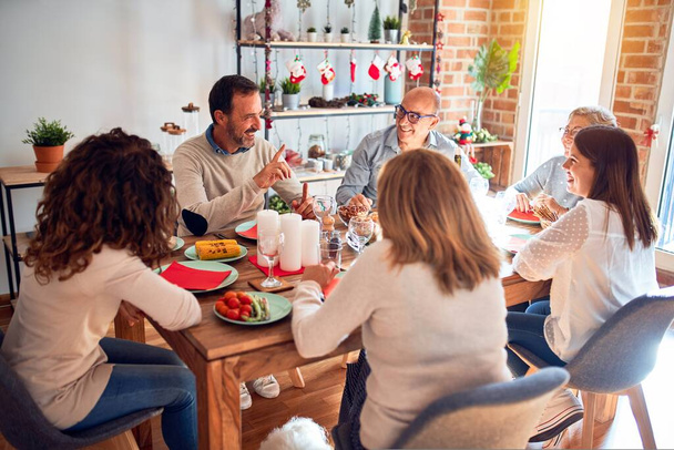 Familie en vrienden dineren thuis viert kerstavond met traditioneel eten en decoratie, viering van feestelijke wintertijd - Foto, afbeelding