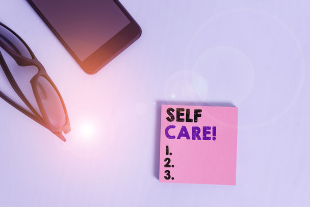 Text sign showing Self Care. Conceptual photo the practice of taking action to improve one s is own health Dark eyeglasses colored sticky note smartphone fashion pastel background. - 写真・画像