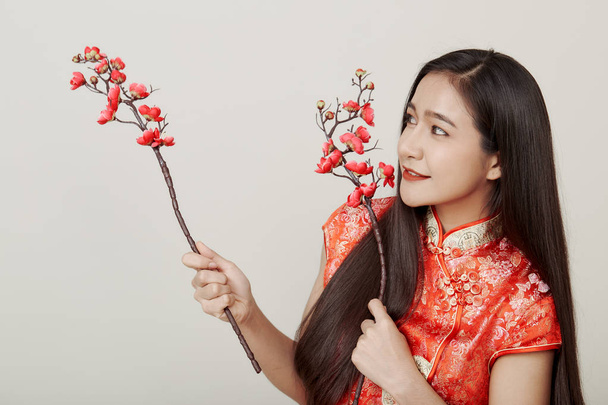 Frau in traditionellem chinesischem roten Kleid mit Pflaumenblüten - Foto, Bild