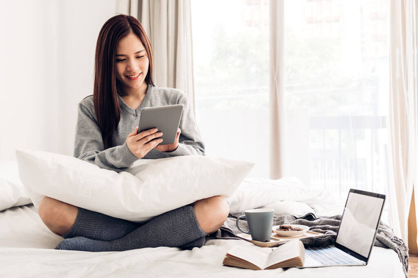 Mulher feliz relaxante usando computador tablet na cama em home.te
 - Foto, Imagem