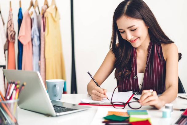 Sorrindo mulher asiática designer de moda trabalhando com computador portátil
 - Foto, Imagem