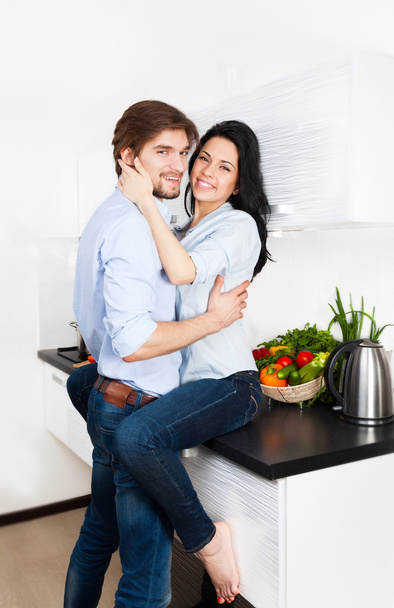 Couple embrace their kitchen home - Zdjęcie, obraz