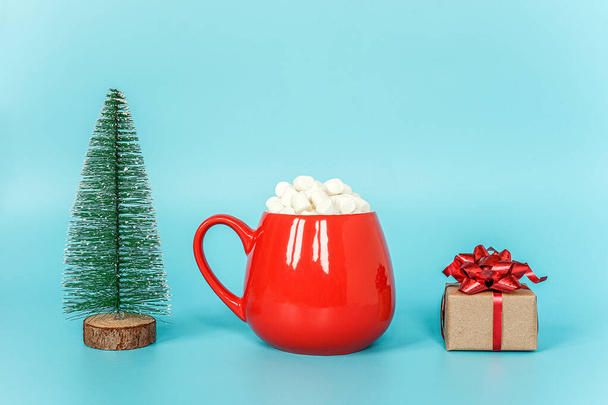 Christmas tree, cup of marshmallow and gift box on blue background. Merry Christmas or Happy New Year concept. Copy space Template for your design, Greeting card - Photo, Image