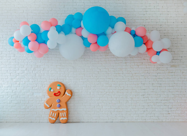 balloons and ice cream cart on festive white brick background with big gingerbread man. - Φωτογραφία, εικόνα