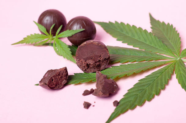 cannabis chocolates and green leaf on pink background.medical marijuana coffee sweets to enhance mood and relaxation - Photo, Image