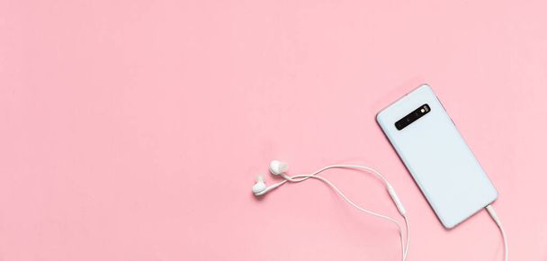 Smartphone y auriculares contra fondo rosa
 - Foto, imagen