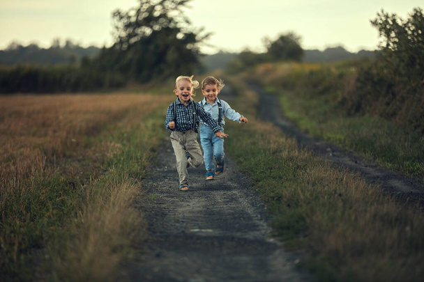 Two adorable boys running on the country road - Photo, Image