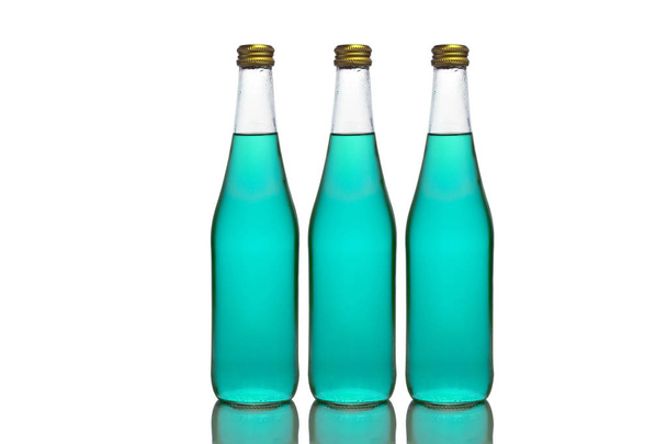 Trois grandes bouteilles en verre avec du liquide bleu clair se tiennent sur une surface miroir sur un fond blanc au milieu
. - Photo, image