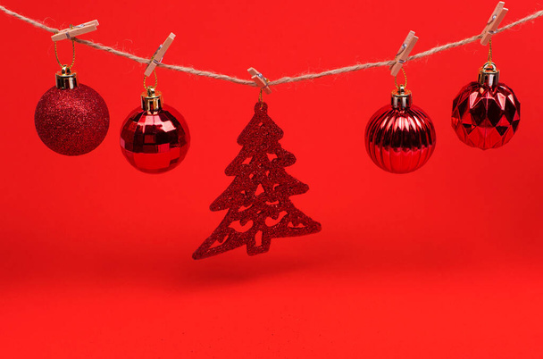 Red Christmas toys balls on a string with clothespins on a red background, preparing for the new year and Christmas - Фото, зображення