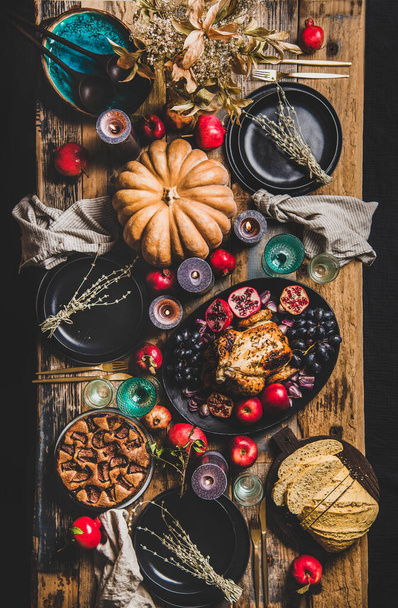 収集のための感謝祭パーティーテーブル設定。ローストチキン、野菜、イチジクパイ、フルーツ、カボチャ、キャンドル、食器、素朴な木製のテーブルの背景に銀食器のフラットレイアウト、トップビュー - 写真・画像