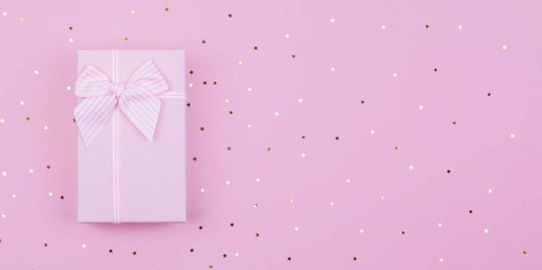 Pink Gift of aanwezig doos en sterren confetti op roze achtergrond. Platte lay compositie voor verjaardag Nieuwjaar, kopiëren spase - Foto, afbeelding