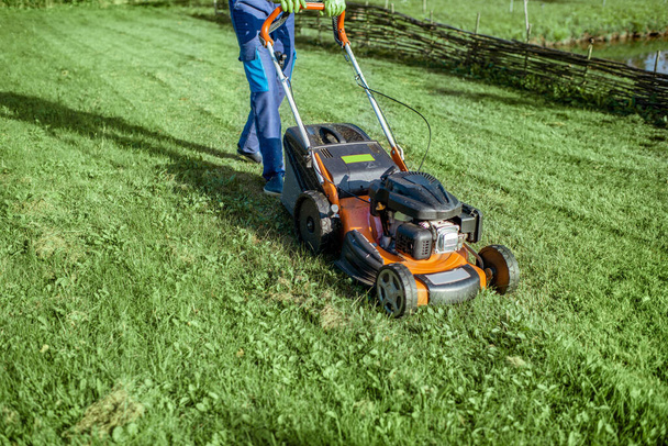 Bahçıvan çim biçme makinesiyle çim biçiyor. - Fotoğraf, Görsel