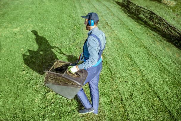 Jardineiro trabalhando com cortador de grama no quintal
 - Foto, Imagem