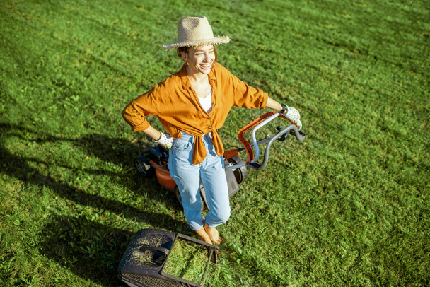 Woman with lawn mower on the backyard - Φωτογραφία, εικόνα
