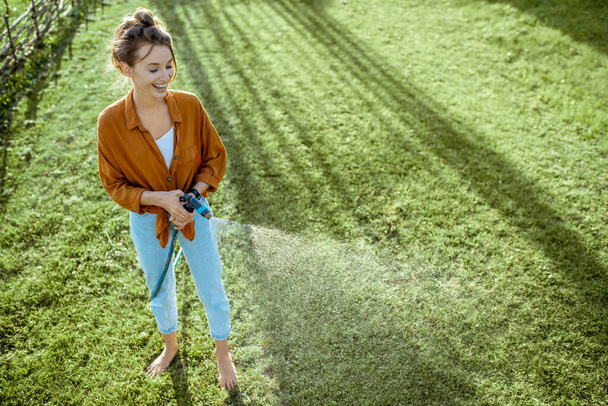 Woman watering green lawn - Photo, Image