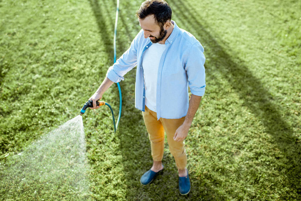 Homem molhando gramado verde
 - Foto, Imagem