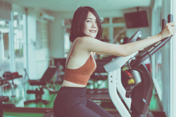 Sağlıklı yaşam tarzı konsepti, bisiklete binen genç kadın spor salonu içinde kardiyo eğitimi alıyor, mutlu ve gülümsüyor. - Fotoğraf, Görsel