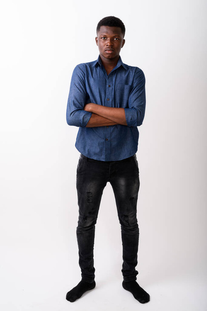 Ganzkörperaufnahme eines jungen schwarzafrikanischen Mannes, der mit den Armen steht cro - Foto, Bild