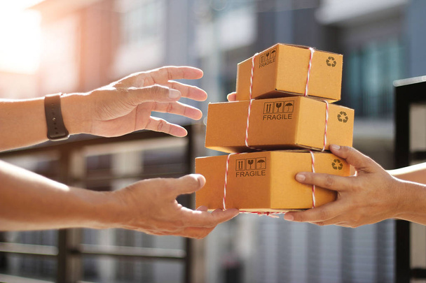 Руки клиента, получающего картонные коробки посылки от курьера
 - Фото, изображение