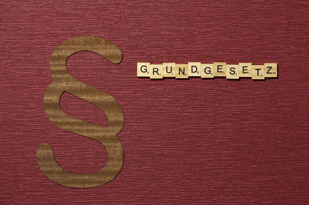Fragment znaku na tle koloru bordo. Słowo po niemiecku Grundgesetz - Zdjęcie, obraz