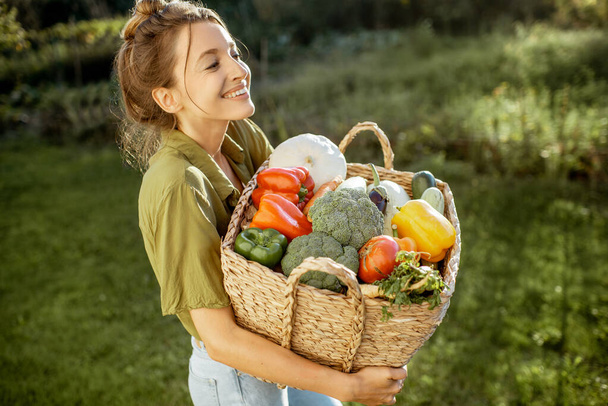 Mladá žena s čerstvou sklizní zeleniny v zahradě - Fotografie, Obrázek