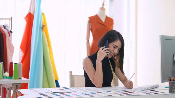 Asiático pequeno empresário falando por telefone enquanto trabalhava no escritório. Loja de roupas e designer de moda
 - Foto, Imagem