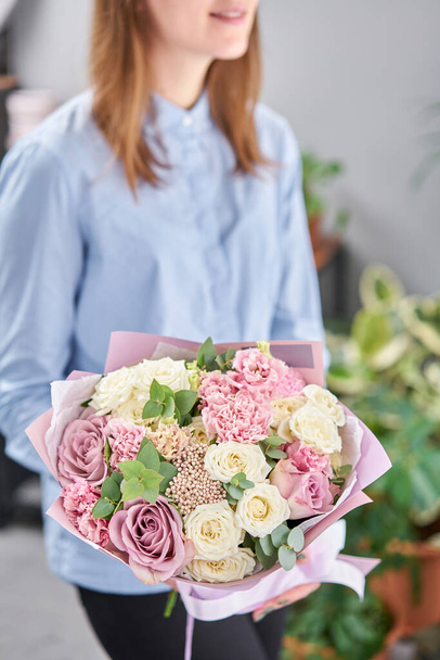 Fehér és rózsaszín szín. Gyönyörű csokor vegyes virág a nők kezében. a virágárus munkája egy virágüzletben. Friss vágott virág. - Fotó, kép
