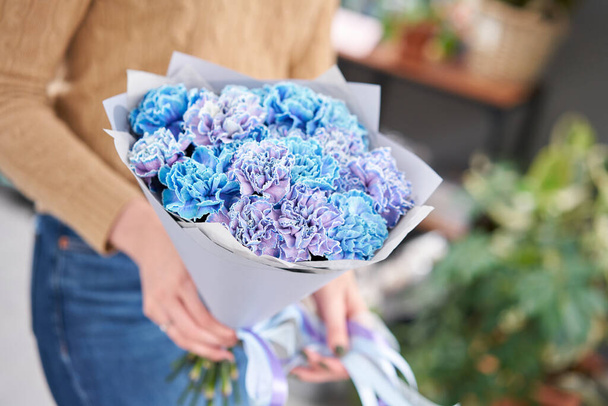 Mono bouquet of blue carnations in woman hand. Unusual flowers dianthus . Spring flower pattern - 写真・画像