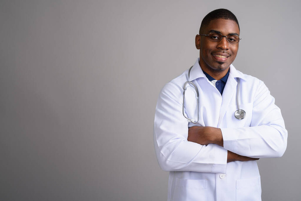 Joven guapo africano hombre médico contra gris fondo - Foto, imagen