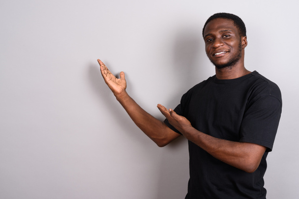 Joven hombre africano con camisa negra sobre fondo gris
 - Foto, imagen