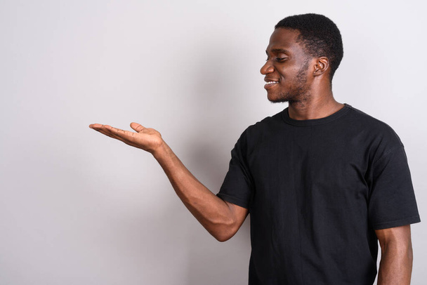 Joven hombre africano con camisa negra sobre fondo gris
 - Foto, Imagen