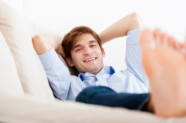 Man lying down on sofa - Фото, изображение