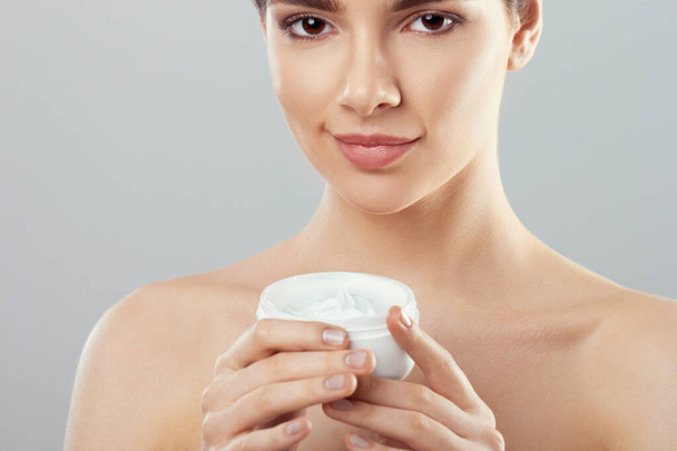 Beautiful Woman With Face Cream. Skin Protection. SkinCare. Spa. A Young Female Holds Moisturizing Cream and Smiling.. Natural Makeup - Zdjęcie, obraz