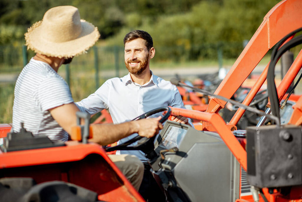 Agronomist with salesman near the tractor outdoors - Foto, imagen