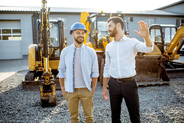 Builder with a sales consultant at the shop with heavy machinery - Foto, imagen