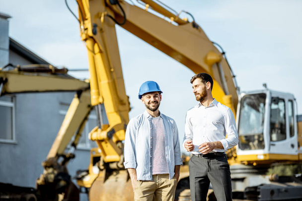 Builder with a sales consultant at the shop with heavy machinery - Photo, Image