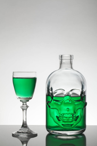 A skull bottle and crystal glasses with a liquid, alcohol drink. - Valokuva, kuva