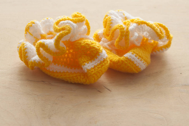 Newborn knitted baby boots on wood background - Photo, Image
