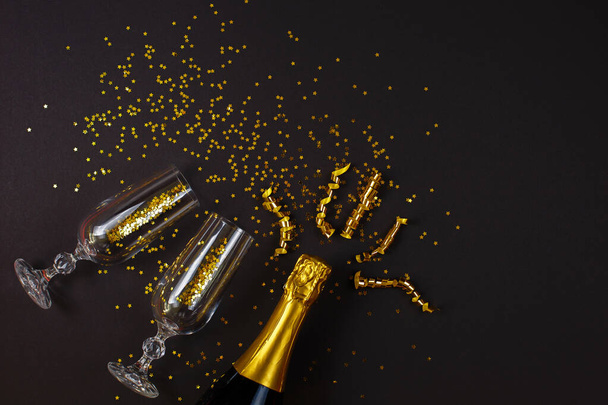 Twee champagne glazen met confetti op zwarte achtergrond. - Foto, afbeelding