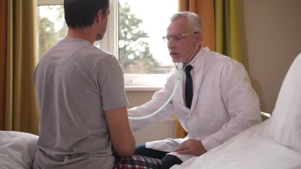 Arzt untersucht Patientin mit Stethoskop auf Station - Filmmaterial, Video