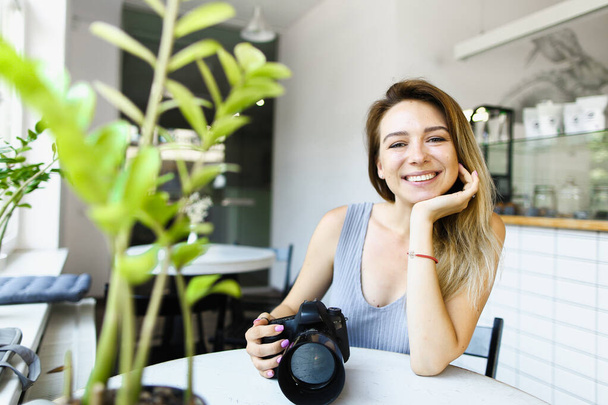 若い女性ヨーロッパの写真家は、カメラとカフェに座ってモデルを待っています. - 写真・画像