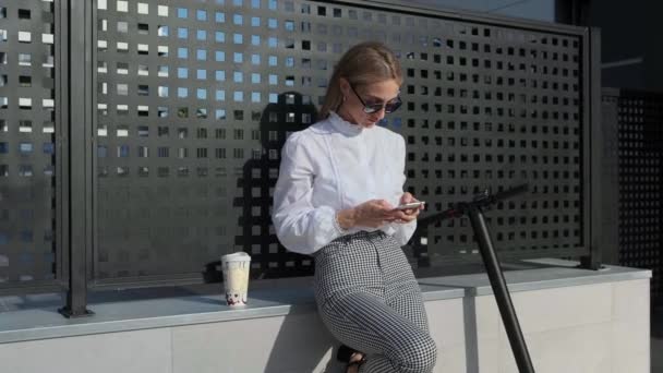 Bizneswoman z telefonu komórkowego i jej skuter następny - Materiał filmowy, wideo