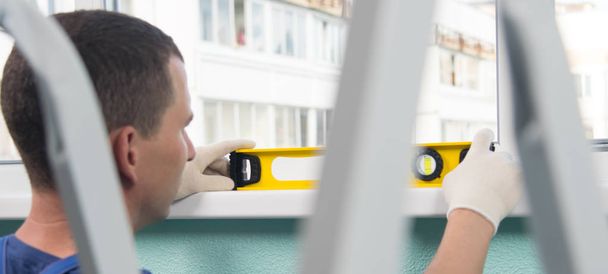 on the background of the stairs, the master checks the yellow level of the correct installation of the window sill, close-up - Fotografie, Obrázek