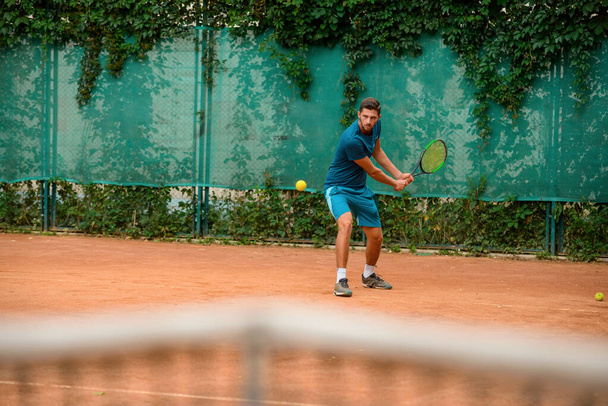 Skilled male tennis player at outdoor court - Photo, image