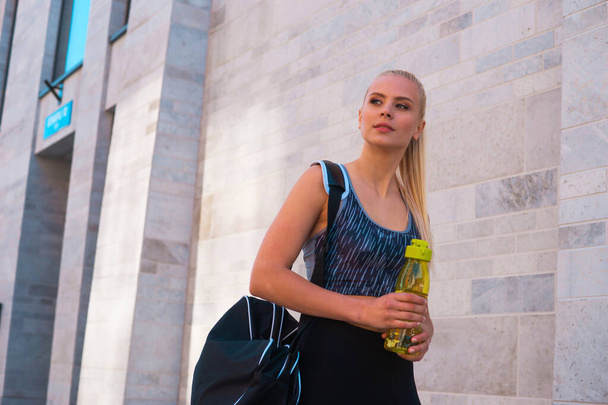 Attractive woman in sportswear walking to a gym outdoor. Sport, jogging, healthy and active lifestyle concept. - Φωτογραφία, εικόνα