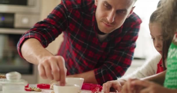 Handheld view of dad and his little daughter decorating cookies  - Filmmaterial, Video