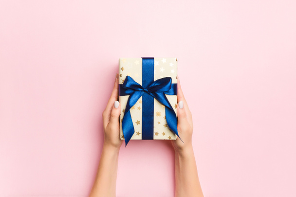 Female's hands holding striped gift box with colored ribbon on l - Photo, Image