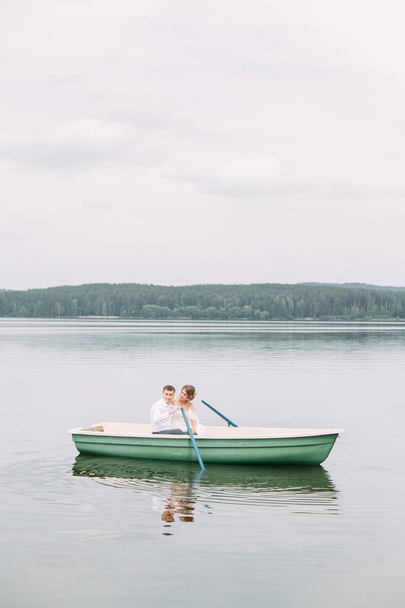  Stylish wedding in European style. Happy couple on a boat on the lake. - Foto, Imagen