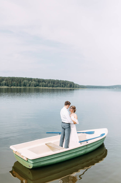  Stylish wedding in European style. Happy couple on a boat on the lake. - Zdjęcie, obraz